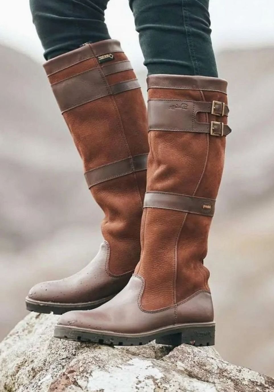 Women's waterproof knee-high country boots by Homixa with double buckles, pull-on style, and two-tone upper design.