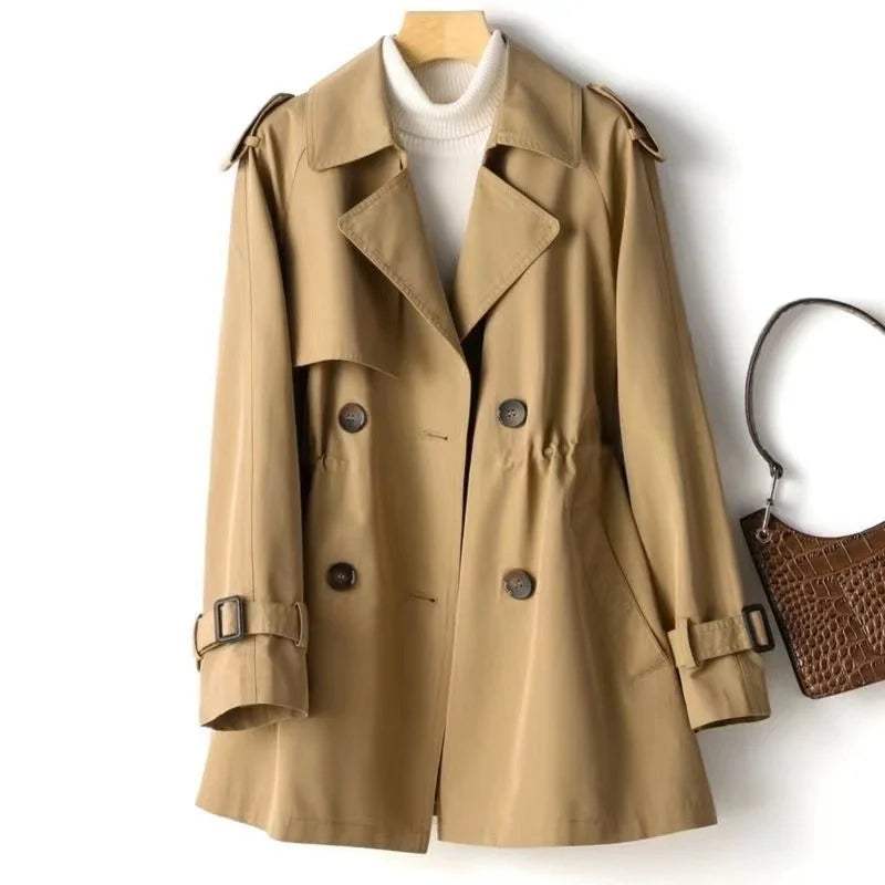 Sweet Emily trench coat by Jack Hafford, beige long double-breasted coat with belt and classic collar, hanging on a wooden hanger.