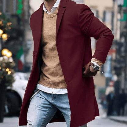 Men's tailored long overcoat by Homixa with notched lapel and button-front closure, shown on a model in a casual setting.
