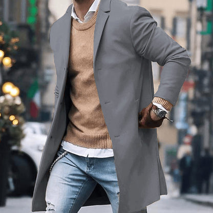 Men's tailored long overcoat by Homixa with notched lapel and button-front closure, shown on a model in a city setting.
