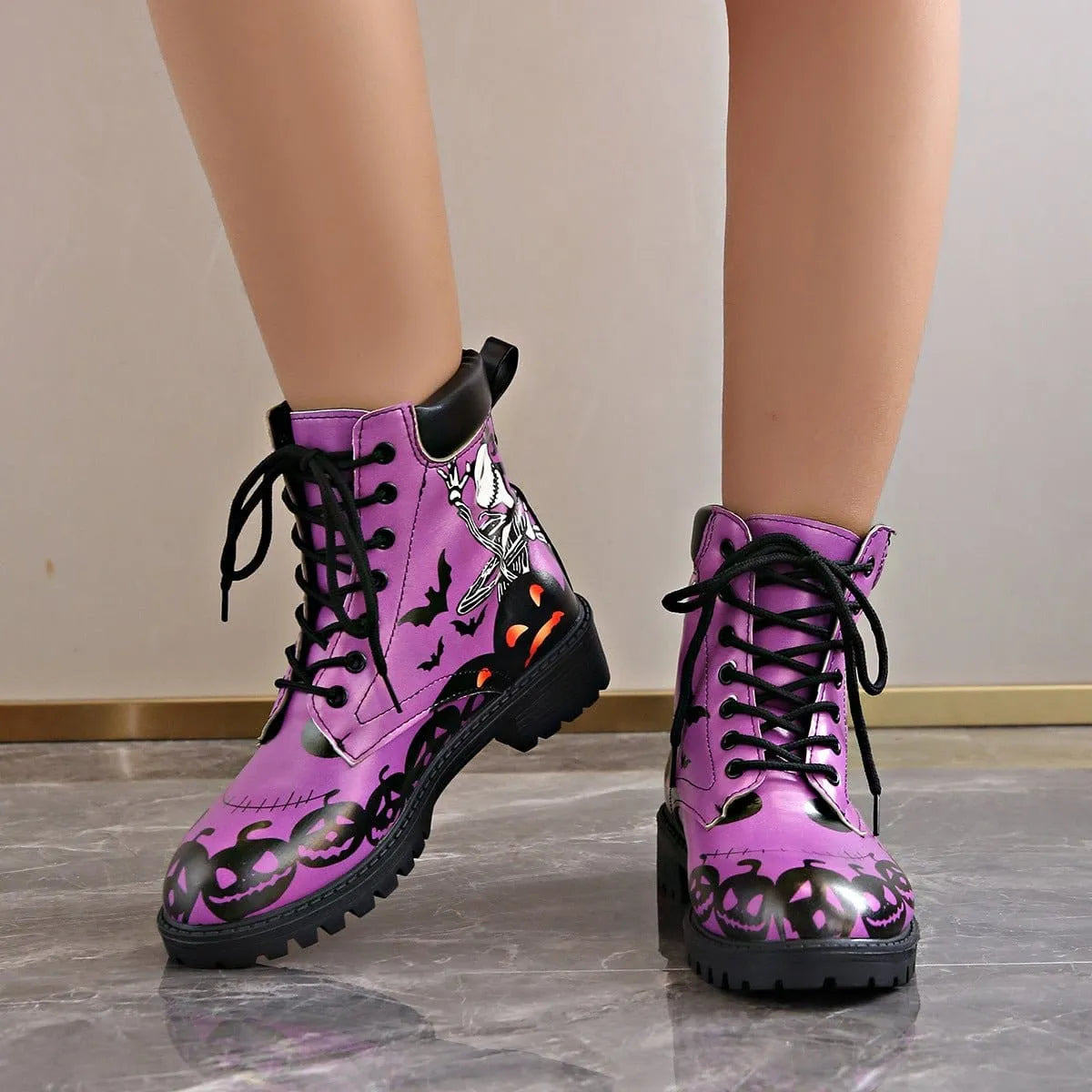 Women's Halloween combat boots by Homixa featuring skeleton, pumpkin, and bat lace-up design on black footwear.