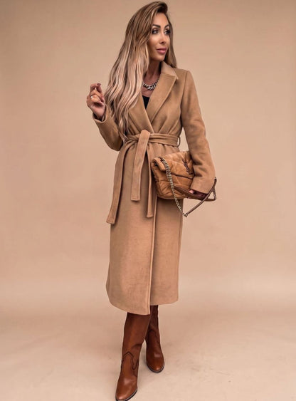 Women's belted knee-length trench coat by Homixa featuring notched lapels and wool-blend fabric, displayed hanging on a coat rack.