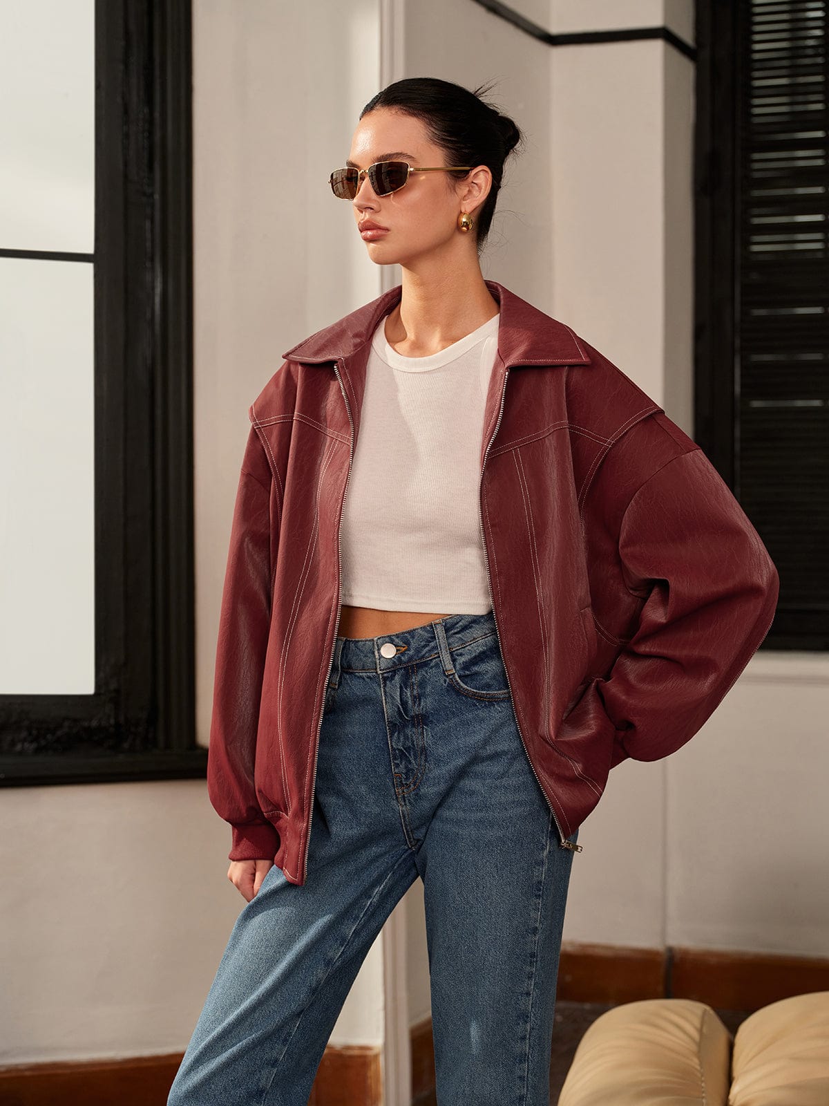 Women's burgundy vegan leather zip-front jacket by Homixa with clean lines and sporty accents, displayed on a hanger.