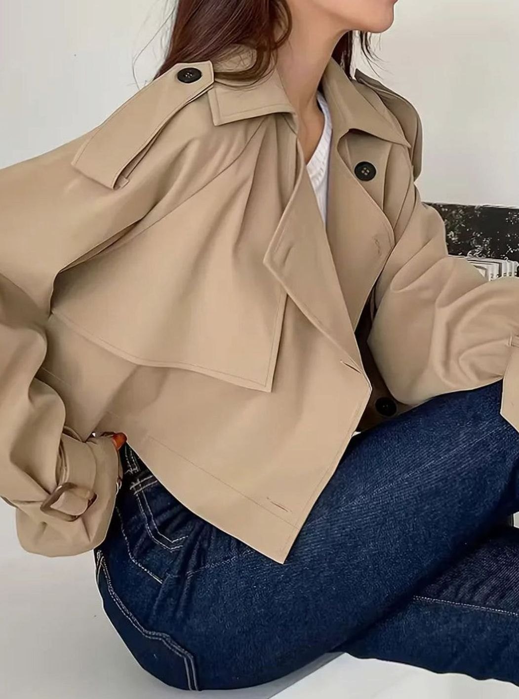 Women's cropped double-breasted trench coat by Homixa with lapels and adjustable cuffs, shown hanging on a neutral background.