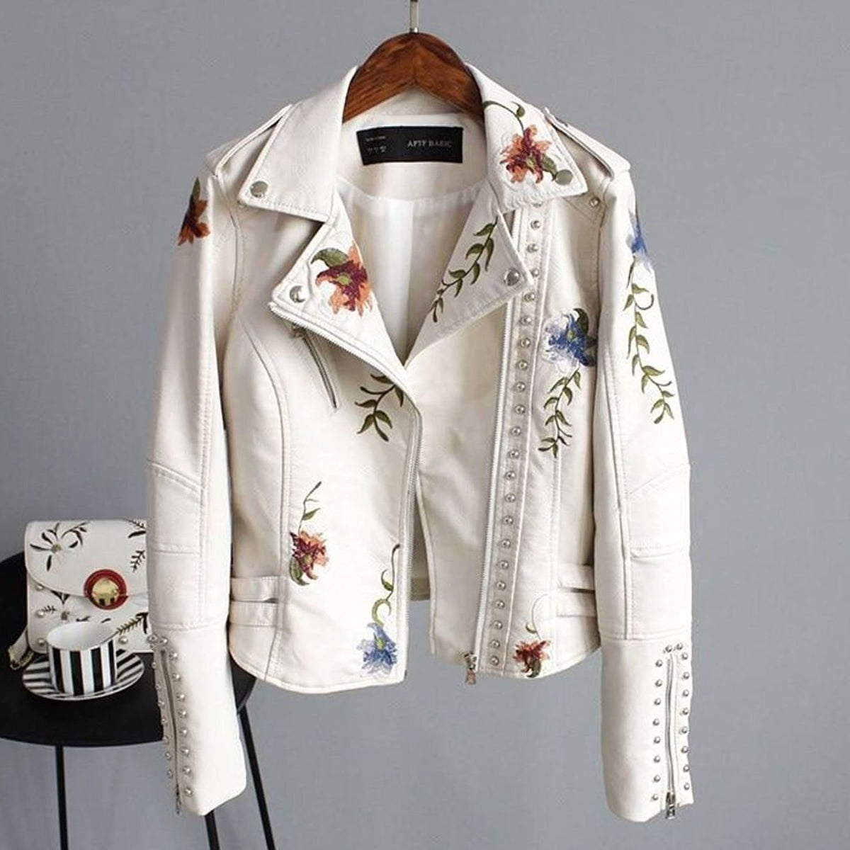 Women's cropped faux-leather moto jacket by Homixa with floral embroidery and metal studs, styled as a trendy biker jacket.