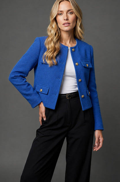 Women's cropped tweed blazer jacket by Homixa with gold buttons and flap pockets, shown on a model.