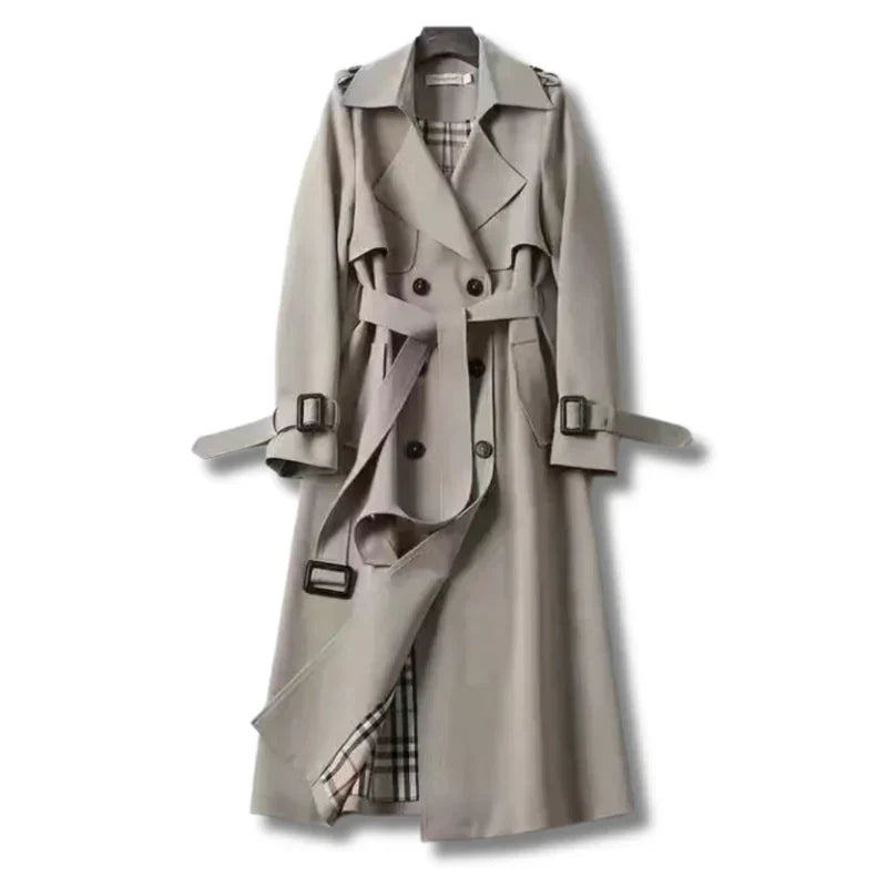 Women’s double-breasted trench coat by Homixa with belt, buckled cuffs, and plaid lining, displayed hanging on a rack.