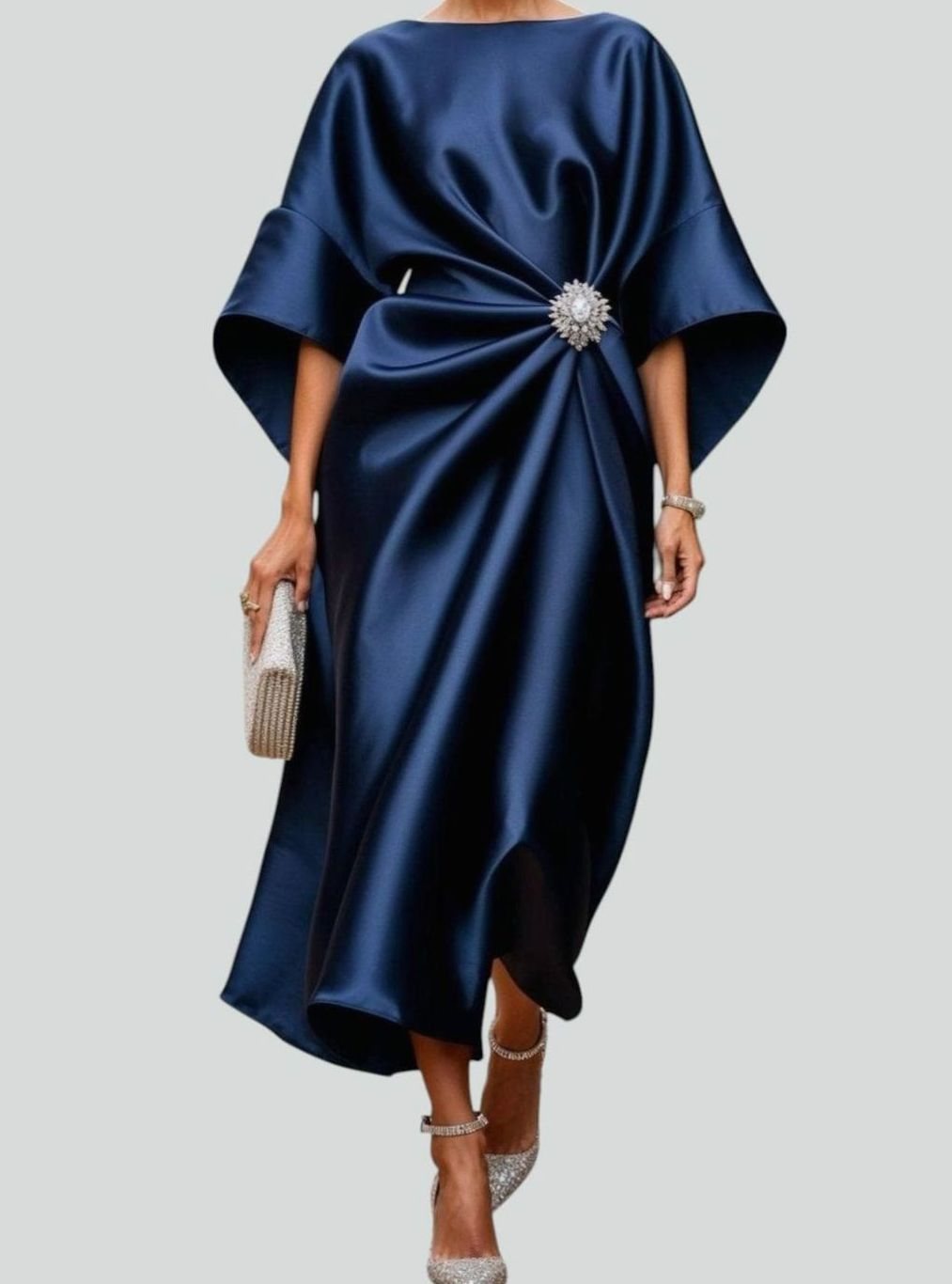 Women's satin midi dress by Homixa featuring draped fabric, batwing sleeves, and a waist brooch, shown on a model.