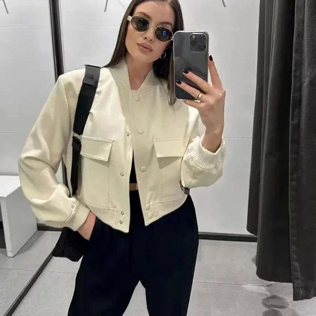 Women's faux-leather bomber jacket by Homixa with snap buttons, patch pockets, and ribbed collar, displayed on a hanger.