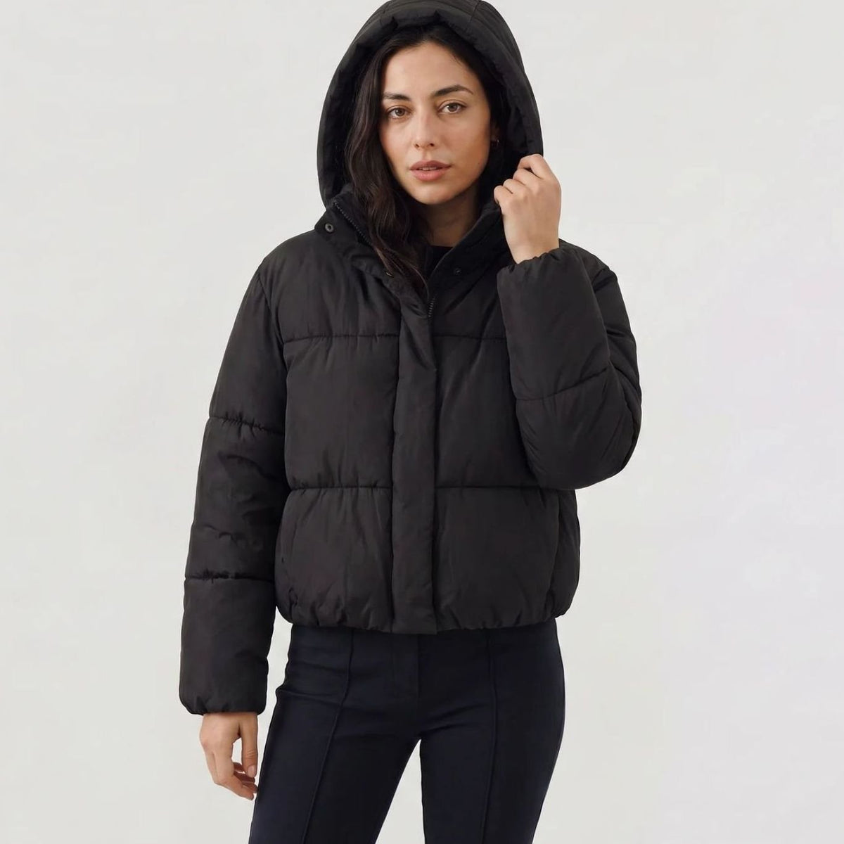 Women’s Homixa full-zip cropped puffer jacket with hood, boxy fit, and quilted shell, shown on a model in a casual outdoor setting.