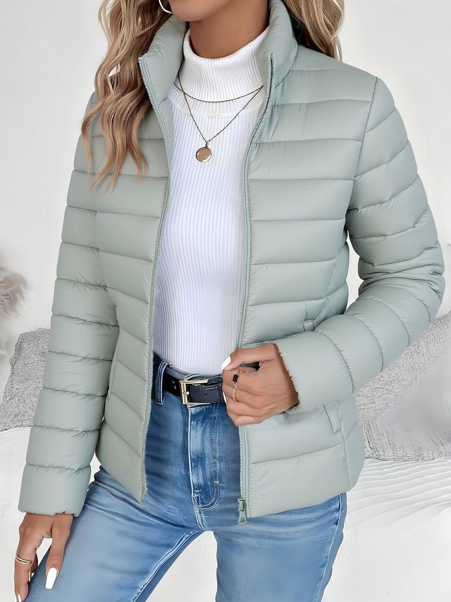 Women's full-zip quilted winter jacket by Homixa with slim fit and stand collar, shown in a stylish outdoor setting.