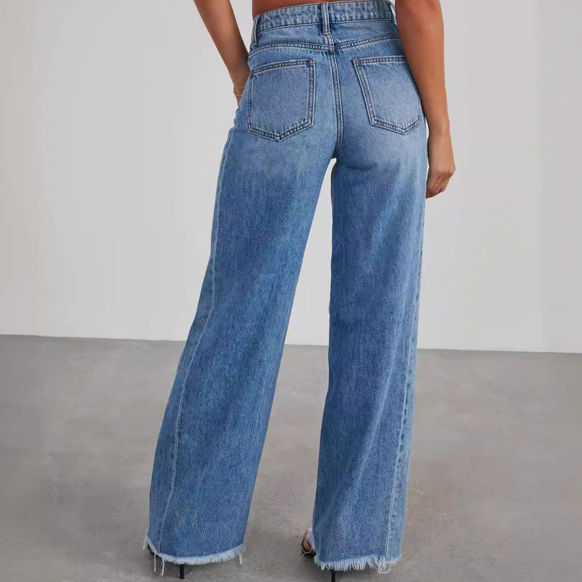 Women's high-waisted wide-leg jeans by Homixa featuring denim fabric and raw frayed hem, styled on a model.