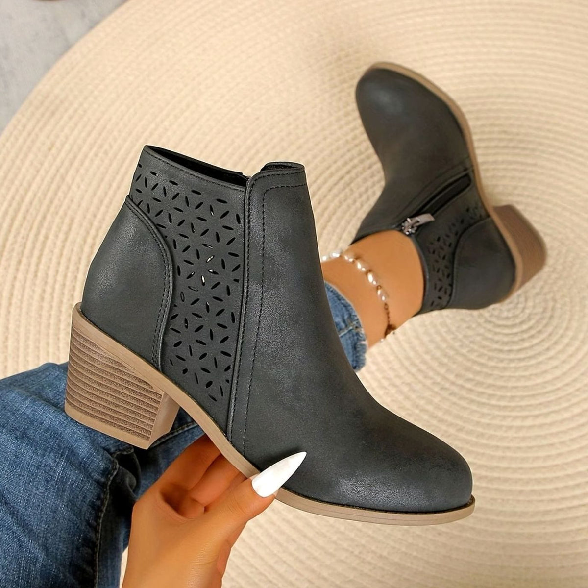 Women's laser-cut booties by Homixa with floral cutouts, block heel, and side zipper, showcasing stylish and intricate design details.