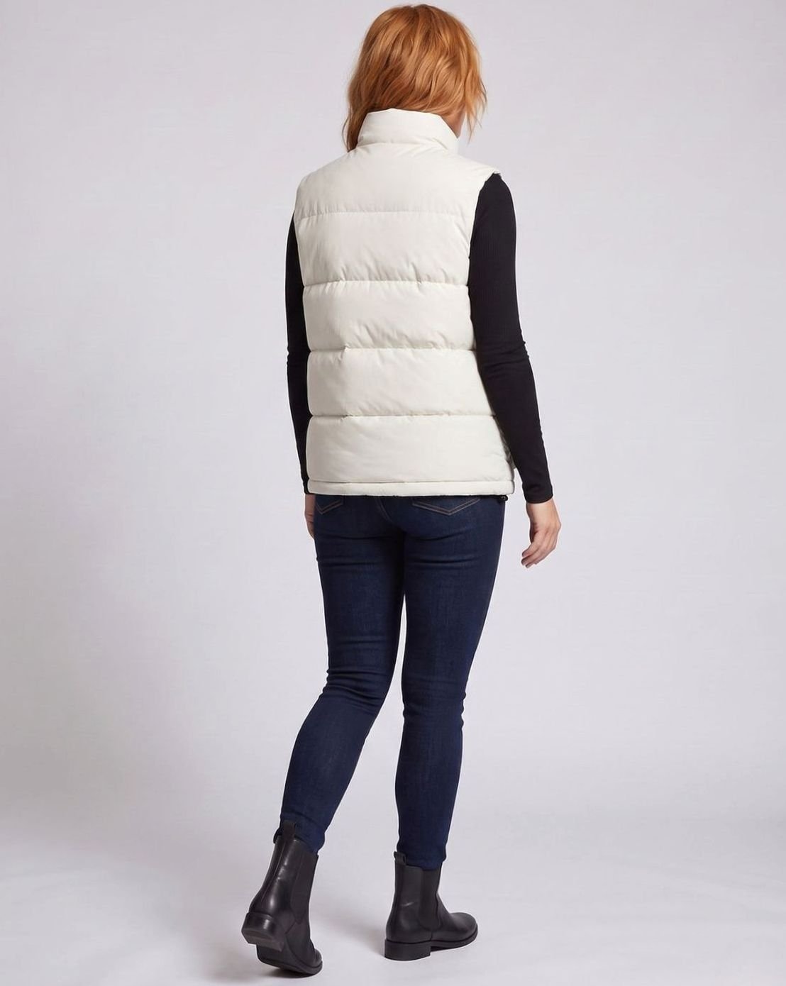 Women's quilted puffer vest by Homixa with funnel neck, concealed zipper, and large flap pockets, shown in a stylish outdoor setting.